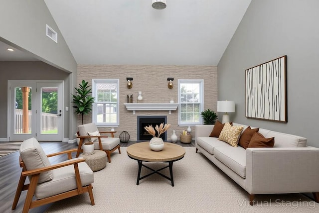 living area featuring high vaulted ceiling, a fireplace, and wood finished floors