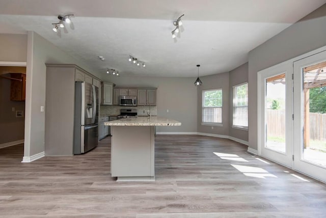 kitchen with stainless steel appliances, baseboards, light countertops, tasteful backsplash, and light wood-style flooring