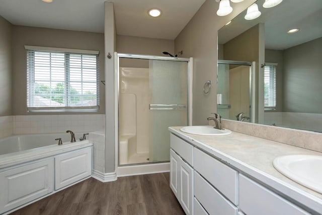 full bathroom with a shower stall, wood finished floors, double vanity, a garden tub, and recessed lighting