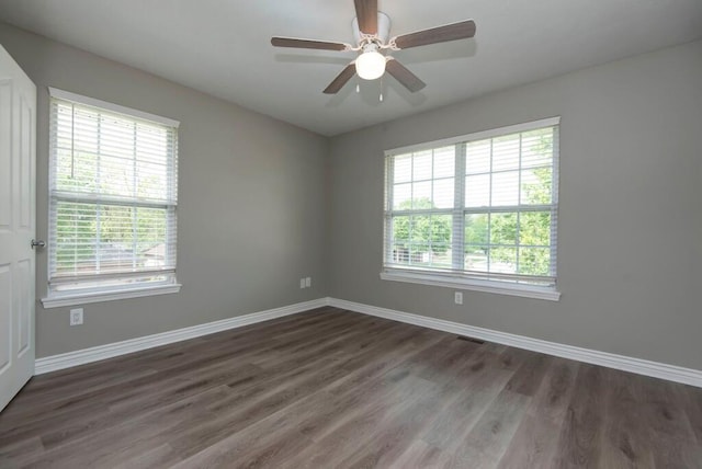 empty room with healthy amount of natural light, wood finished floors, and baseboards