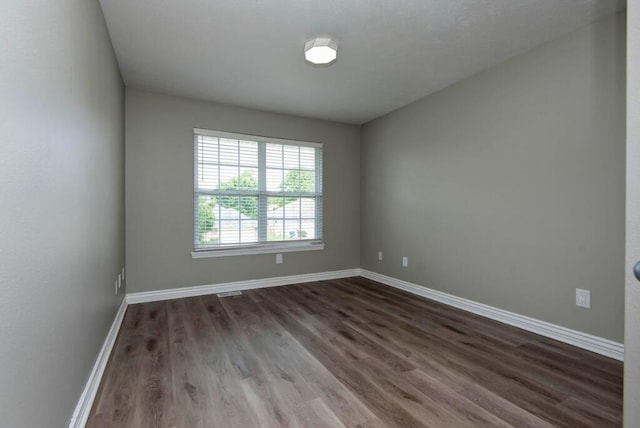 empty room featuring dark wood-type flooring and baseboards