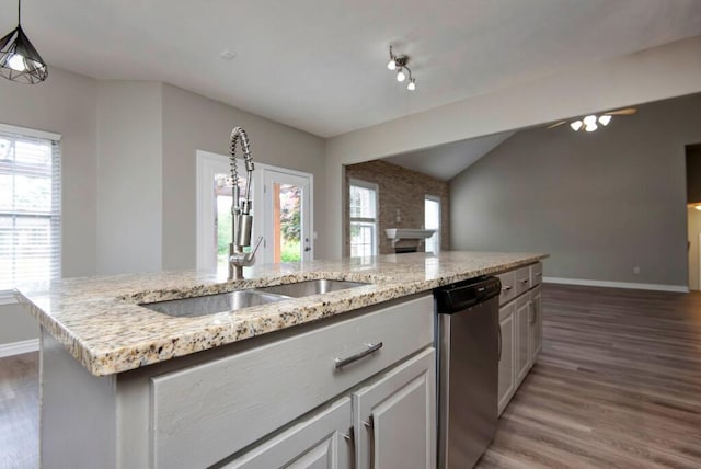 kitchen featuring stainless steel dishwasher, a sink, light wood-type flooring, baseboards, and lofted ceiling