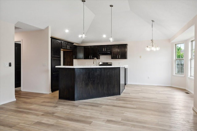 kitchen featuring under cabinet range hood, lofted ceiling, a chandelier, light countertops, and stainless steel electric range oven