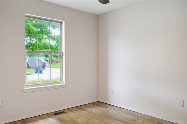 empty room featuring plenty of natural light, light wood finished floors, ceiling fan, and baseboards