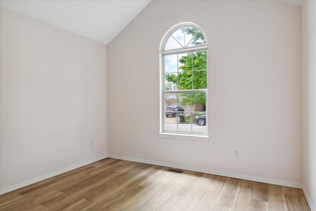 spare room with light wood-style floors, vaulted ceiling, and baseboards