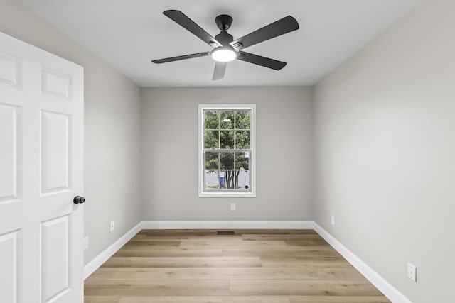 spare room with baseboards, light wood finished floors, and ceiling fan