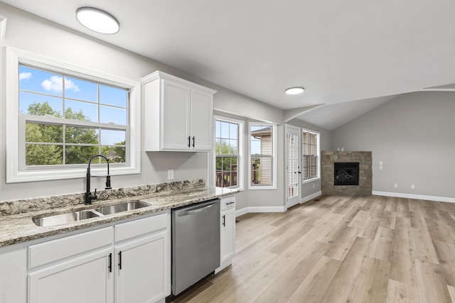 kitchen featuring dishwasher, a sink, light wood-style flooring, white cabinetry, and light stone countertops