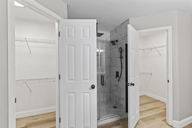 bathroom featuring a stall shower, wood finished floors, and baseboards