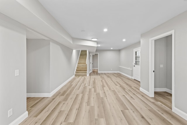 finished below grade area featuring recessed lighting, baseboards, stairway, and light wood-style floors