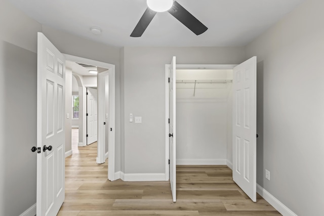 unfurnished bedroom featuring light wood finished floors, baseboards, a closet, and a ceiling fan