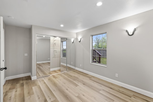 unfurnished bedroom with light wood-type flooring, recessed lighting, baseboards, and a closet