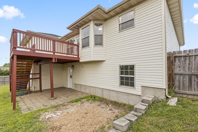 back of property featuring fence, a wooden deck, a patio area, and stairway