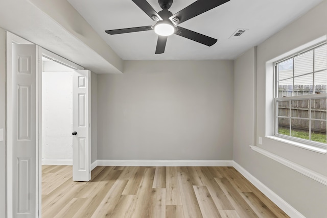 empty room featuring baseboards, light wood finished floors, and healthy amount of natural light
