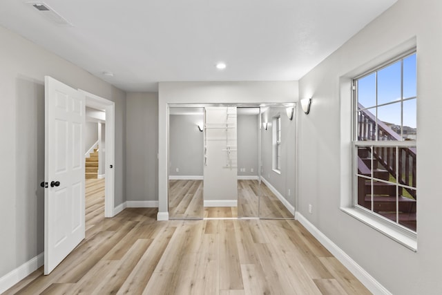 unfurnished bedroom featuring baseboards, light wood-style flooring, recessed lighting, and a closet