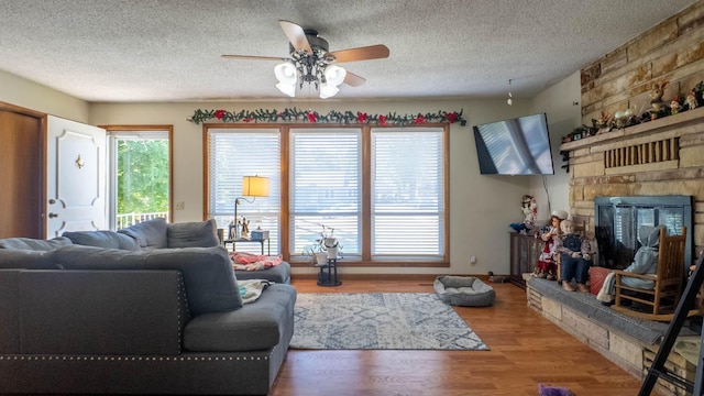 920 Oak St, Thayer, MO 65791 - living area with a ceiling fan, a stone fireplace, a textured ceiling, and wood finished floors