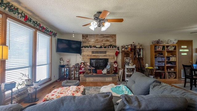 920 Oak St, Thayer, MO 65791 - living room with a ceiling fan, a textured ceiling, a stone fireplace, and wood finished floors