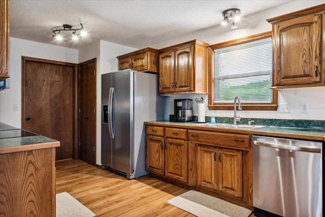 1215 E 515th Rd, Morrisville, MO 65710 - kitchen with appliances with stainless steel finishes, a sink, light wood-type flooring, brown cabinets, and a textured ceiling