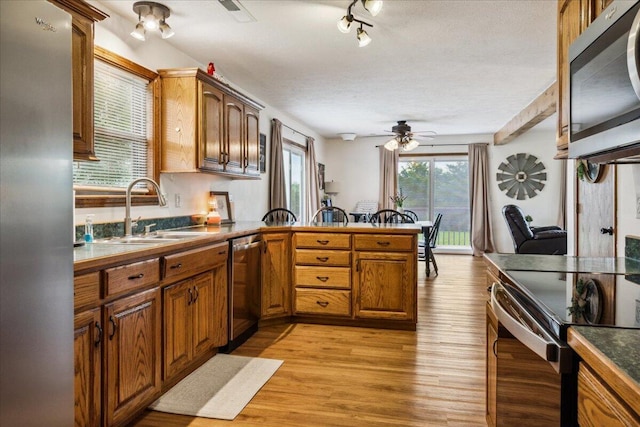 1215 E 515th Rd, Morrisville, MO 65710 - kitchen featuring a sink, stainless steel appliances, a peninsula, brown cabinetry, and light wood-style flooring