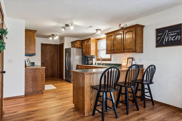 1215 E 515th Rd, Morrisville, MO 65710 - kitchen with stainless steel fridge, light wood-type flooring, a peninsula, and a breakfast bar area