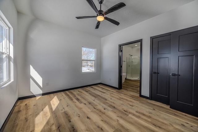 834 Morris St, Mountain Grove, MO 65711 - unfurnished bedroom featuring light wood finished floors, baseboards, ensuite bathroom, and a ceiling fan