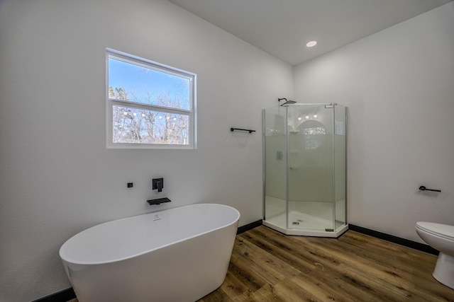 834 Morris St, Mountain Grove, MO 65711 - bathroom featuring wood finished floors, a stall shower, a freestanding tub, baseboards, and toilet