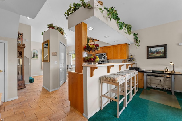 351 Wildwood Dr S Unit 5, Branson, MO 65616 - kitchen with a kitchen breakfast bar, baseboards, light countertops, a peninsula, and brown cabinetry