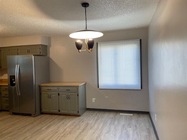1627 W Lindberg St, Springfield, MO 65807 - kitchen featuring stainless steel fridge, a textured ceiling, light wood-type flooring, light countertops, and pendant lighting