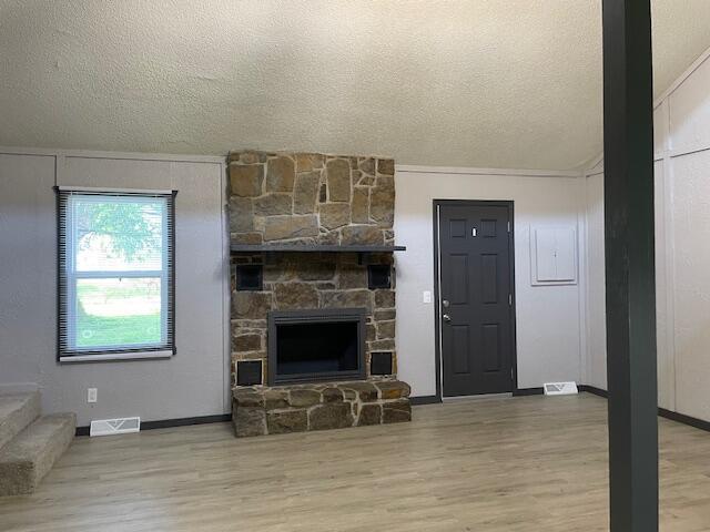 1627 W Lindberg St, Springfield, MO 65807 - unfurnished living room featuring wood finished floors, a textured ceiling, a fireplace, and baseboards