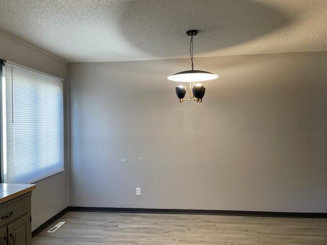1627 W Lindberg St, Springfield, MO 65807 - unfurnished dining area featuring healthy amount of natural light, light wood-style floors, a textured ceiling, and baseboards