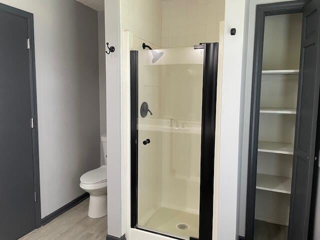 1627 W Lindberg St, Springfield, MO 65807 - bathroom featuring a stall shower, toilet, wood finished floors, and baseboards