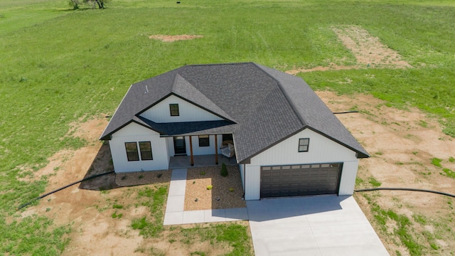 13320 E 1424th Rd, Stockton, MO 65785 - modern inspired farmhouse with concrete driveway, an attached garage, roof with shingles, a porch, and a front lawn
