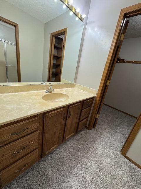 3820 S Virginia Pl, Springfield, MO 65807 - bathroom featuring a textured ceiling, vanity, an enclosed shower, and carpet floors