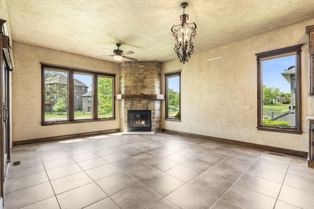 3260 W Rivulet Pass, Springfield, MO 65810 - unfurnished living room with a ceiling fan, a stone fireplace, baseboards, tile patterned floors, and a chandelier