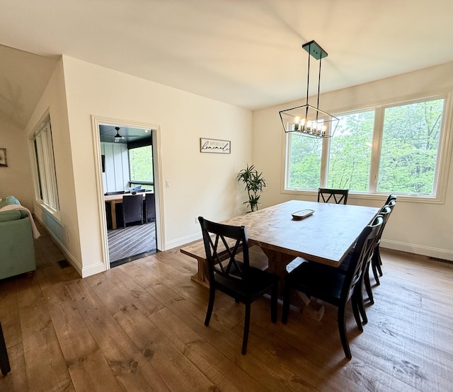 dining area featuring dark wood-style floors, a chandelier, and baseboards