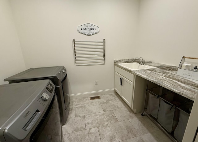 clothes washing area with washing machine and clothes dryer, cabinet space, and baseboards