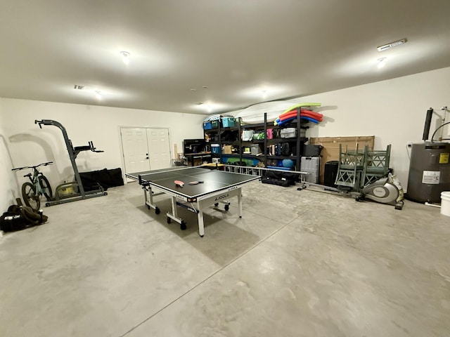 playroom featuring water heater and concrete flooring