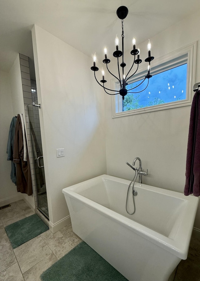 bathroom featuring a chandelier, a shower stall, a freestanding bath, and baseboards