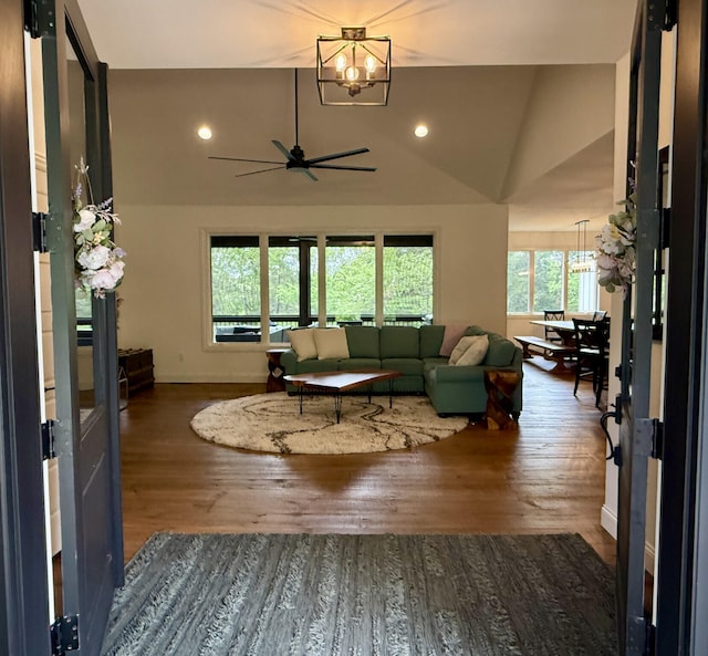 living room with a chandelier, wood finished floors, lofted ceiling, baseboards, and ceiling fan