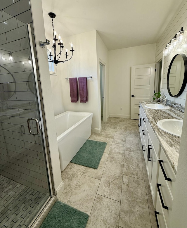 full bath with a bath, a chandelier, a shower stall, double vanity, and baseboards