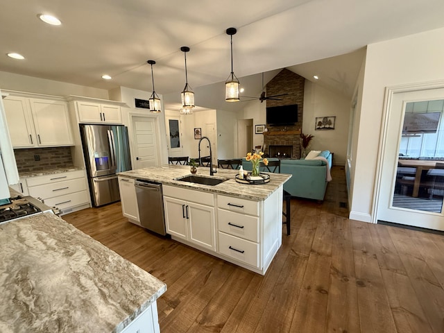 kitchen featuring a sink, appliances with stainless steel finishes, a fireplace, ceiling fan, and white cabinetry