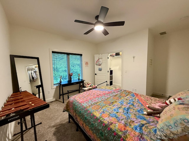 bedroom featuring a walk in closet, a closet, baseboards, carpet, and ceiling fan