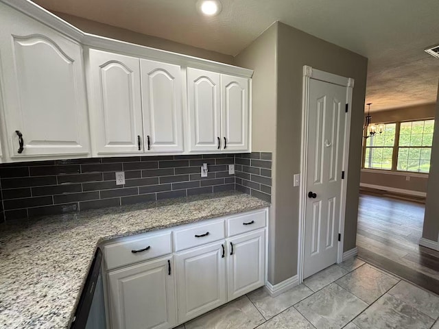 kitchen featuring decorative backsplash, white cabinets, baseboards, and light stone countertops