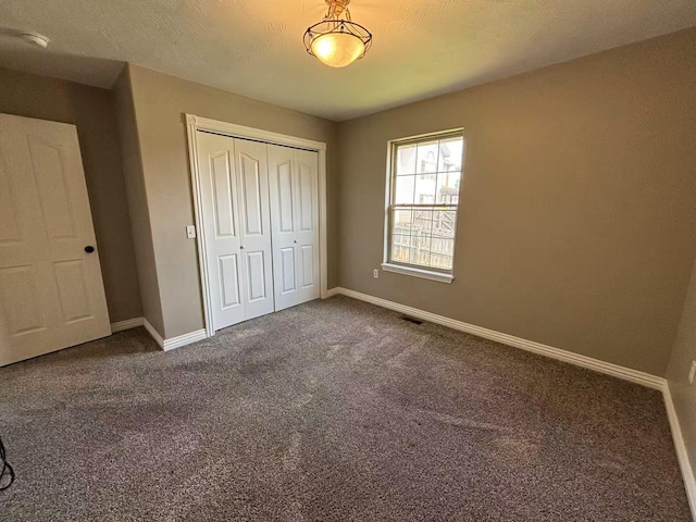 unfurnished bedroom with baseboards, carpet, and a closet