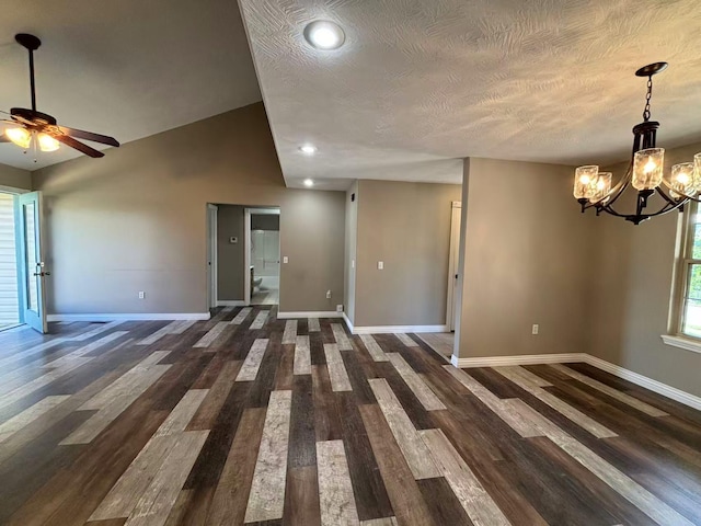 spare room with baseboards, a chandelier, ceiling fan, dark wood-style flooring, and a textured ceiling