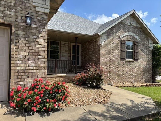 property entrance with roof with shingles, covered porch, and brick siding