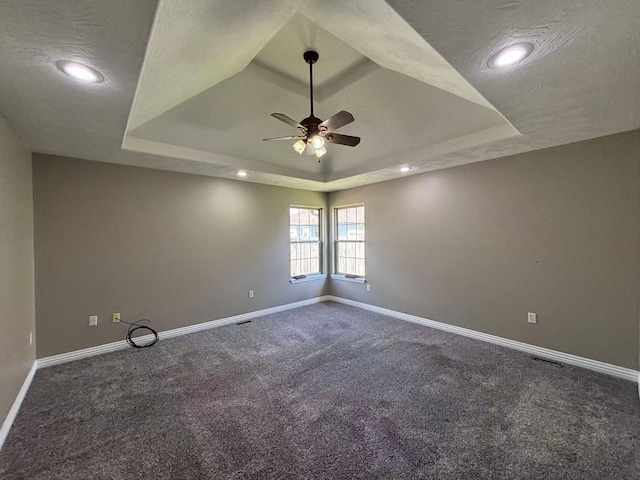 empty room featuring a tray ceiling, ceiling fan, baseboards, carpet flooring, and recessed lighting