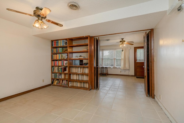empty room featuring ceiling fan, light tile patterned flooring, baseboards, and a textured ceiling