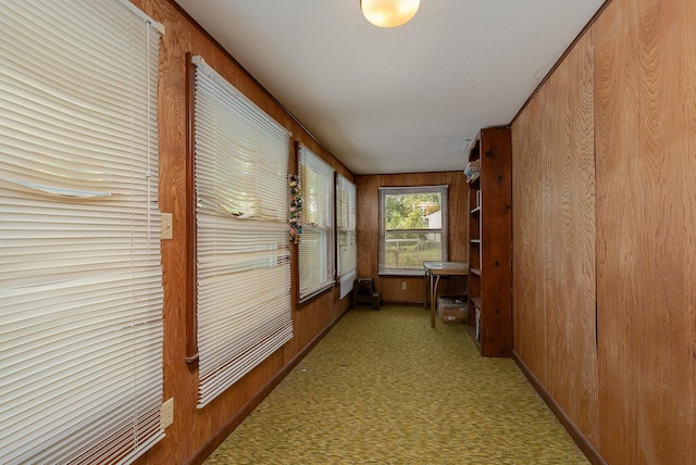 corridor with wood walls, carpet flooring, and baseboards
