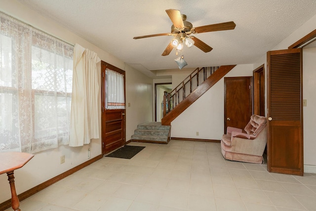 entryway with ceiling fan, baseboards, stairway, and a textured ceiling