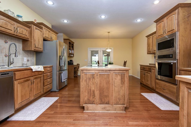 904 W Crater Cir, Nixa, MO 65714 - kitchen featuring appliances with stainless steel finishes, a sink, a kitchen island, wood finished floors, and backsplash